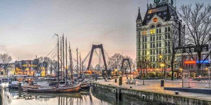 Zonsopkomst op een bijna wolkenloze dag in Rotterdam, met de Willemsbrug, het witte Huis en de Oude Haven