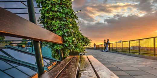 Bankje op het dak van het Groothandelsgebouw tijdens zonsondergang, met op de achtergrond een stelletje in een romantische stemming