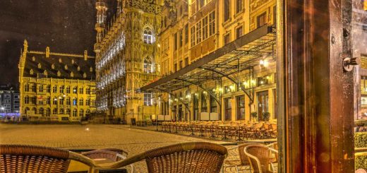 Foto van het Stadhuis en de Grote Markt in Leuven bij avond gemaakt vanachter het raam van een kroeg.