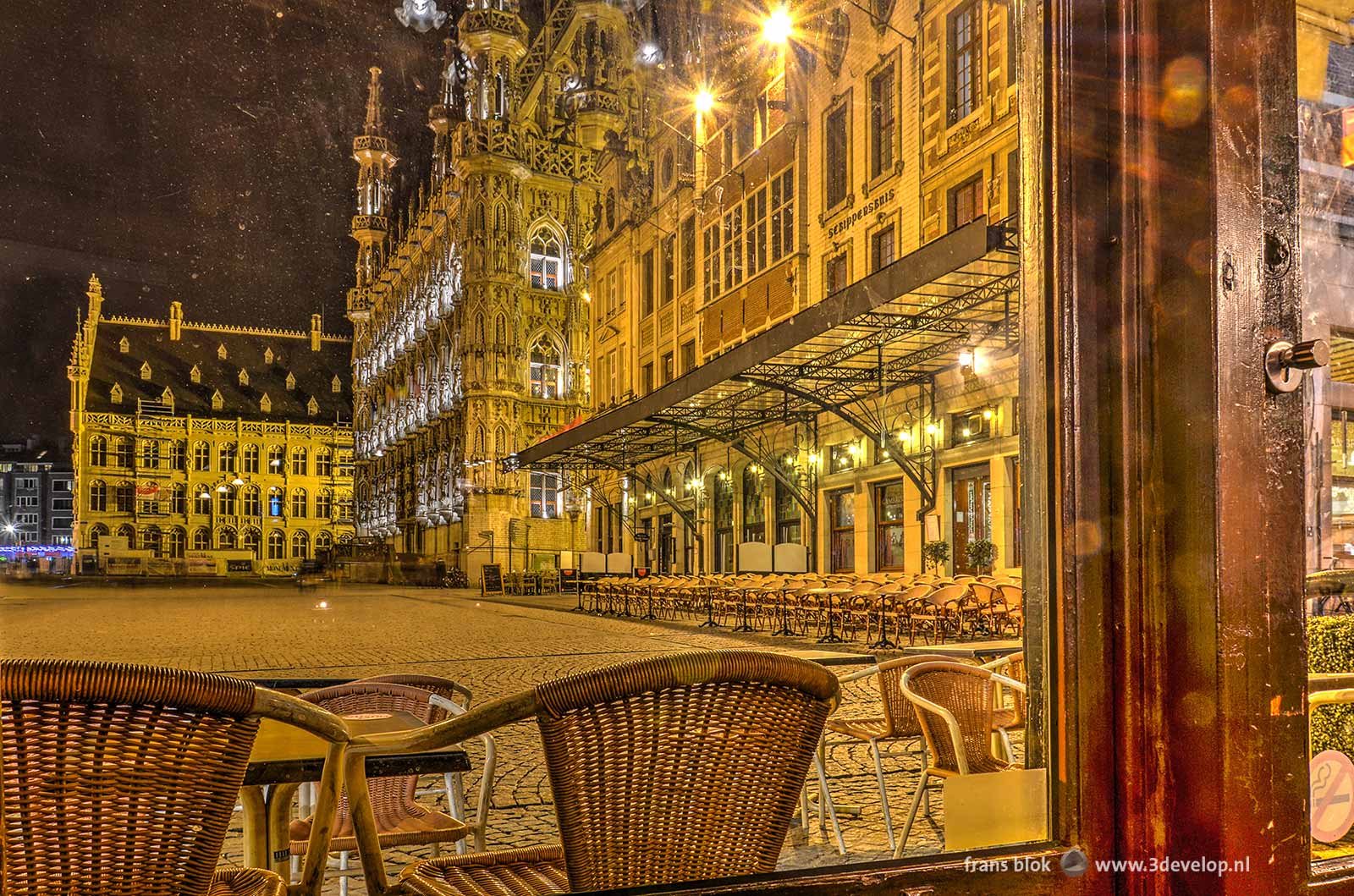 Photo of the City Hall and the Market Square in Leuven made at night through the window of a pub.