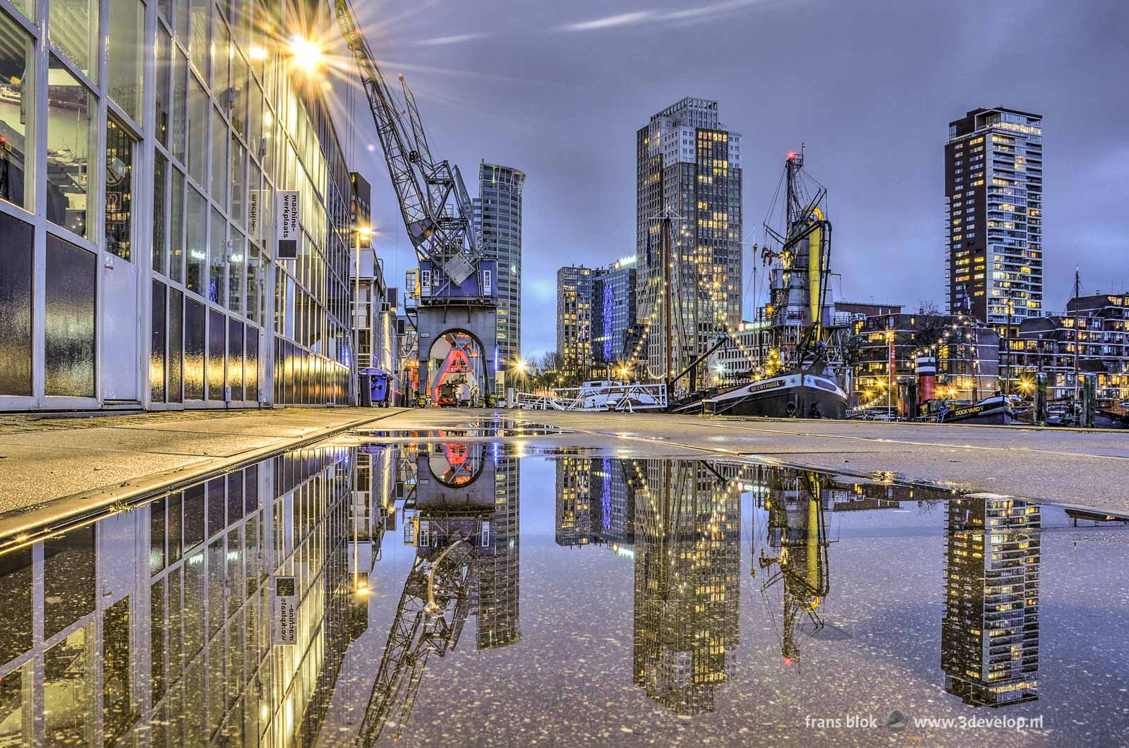 Puddlegram: reflection of cranes, boats, grain elevator as well as office and residential towers in a puddle on the quay at the Maritime Outdoor Museum on Leuvehaven in Rotterdam