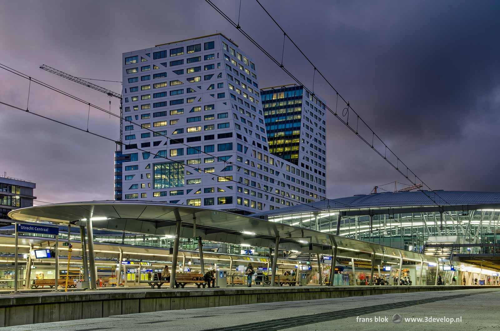 Photo made from one of the platforms on Utrecht Central railway station during the blue hour with the platform canopies, the station hall and the City Office