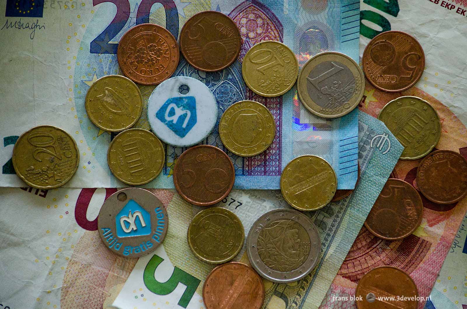 Flatlay van een aantal eurobiljetten en euromunten en een tweetal munten voor de winkelwagentjes van Albert Heijn