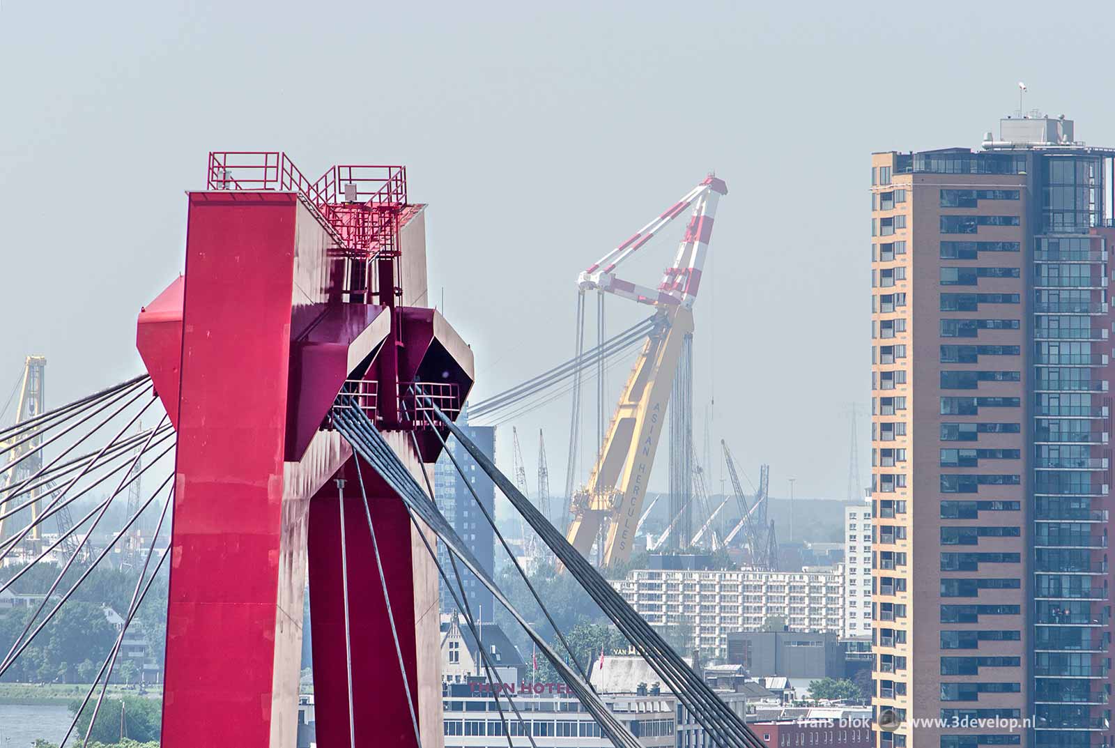 Image made with a telephoto lens showing one of the pylons of willems Bridge in Rotterdam with in the background a residential tower and a large crane in the harbour