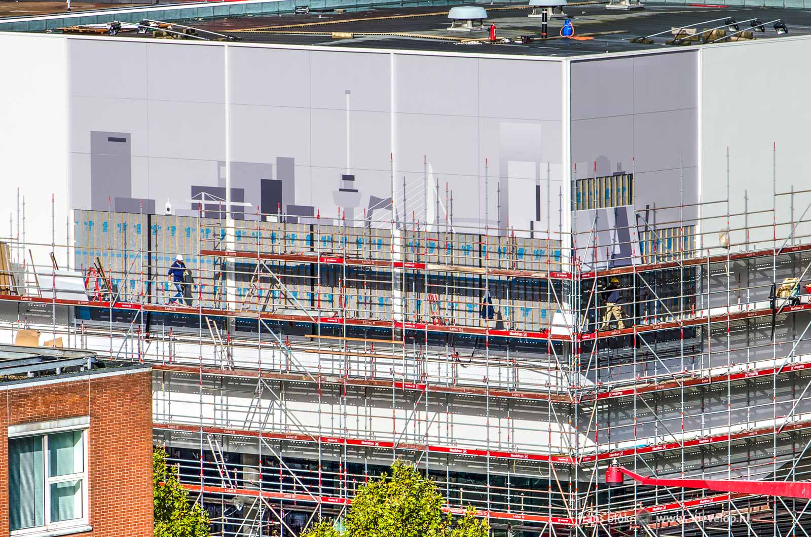 Work in progress on the facade of the Pathé cinema on Schouwburgplein in Rotterdam, where the city's skyline slowly emerges behind the scaffolding