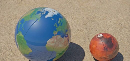 The planets Earth and Mars represented by two beach balls in the sand, on the right scale ratio to each other.