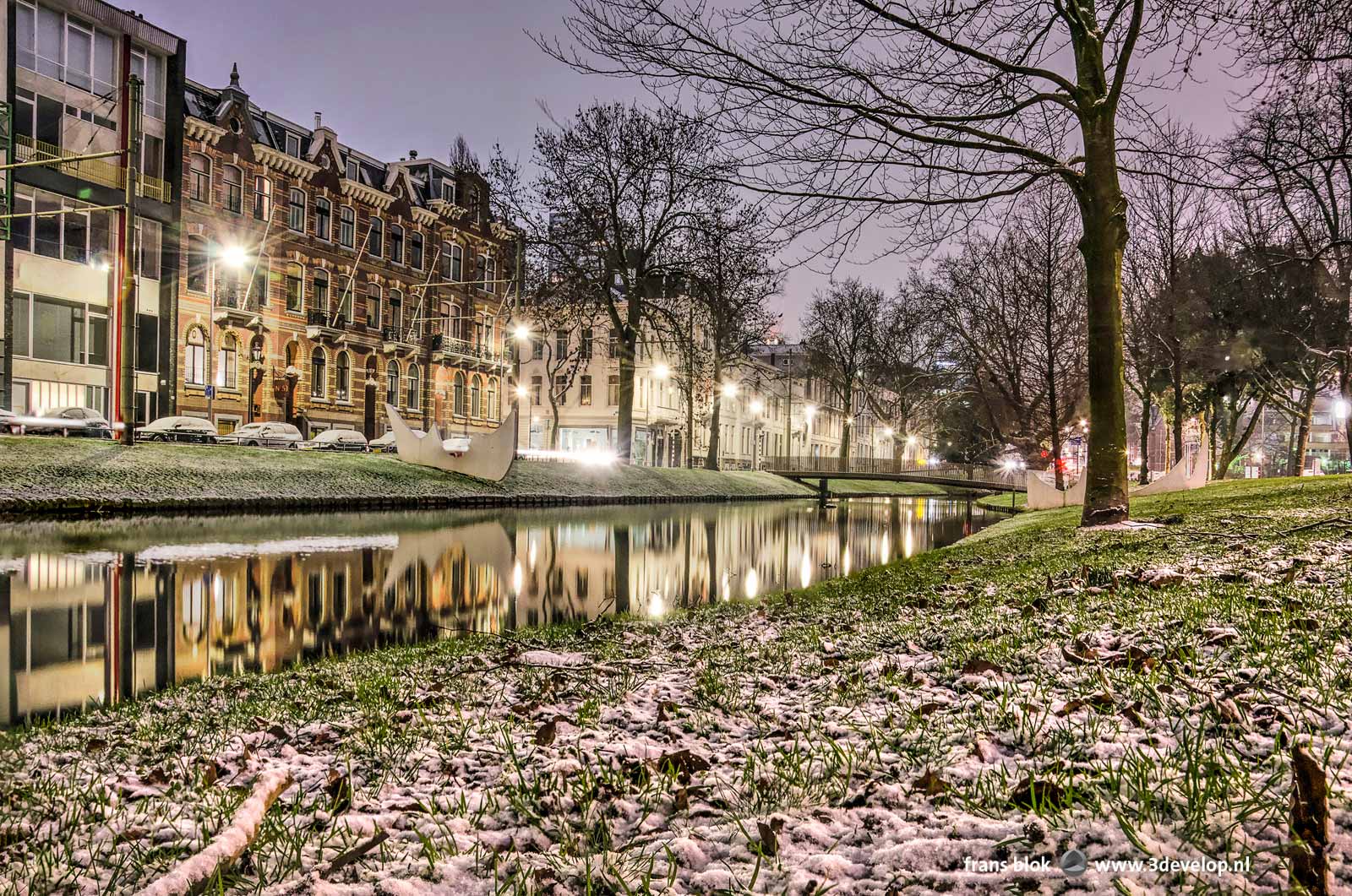 Westersingel canal in Rotterdam in the blue hour before sunset with a very thin layer of snow on the grassy banks