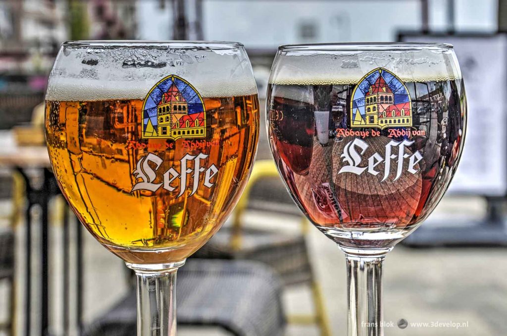 Two glasses of Leffe Belgian beer, one blond and one brown, captured in their natural habitat: a sunny outdoor cafe