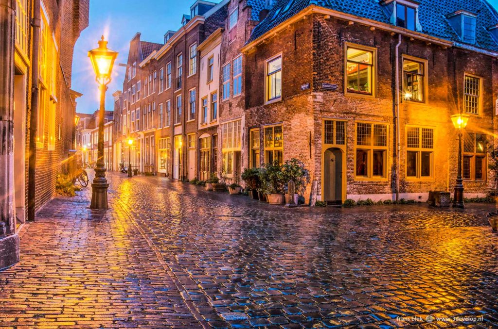 Junction of two narrow, cobble-paved, in the old town of Leyden, The Netherlands, during the blue hour on a rainy night