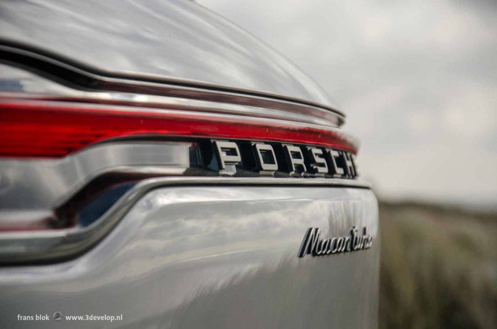 Close up of the rear side of a Porsche Macan Turbo against a blurry nature backgroound