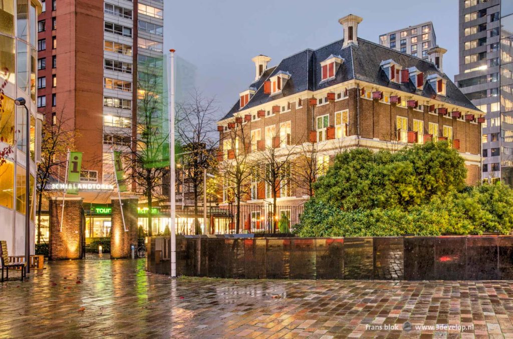 Het zeventiende-eeuwse Schielandshuis in het centrum van Rotterdam tussen moderne hoogbouw gezien vanaf de Coolsingel op een regenachtige avond