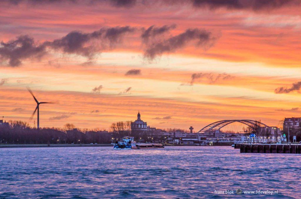 Spectacular sunrive over Nieuwe Maas river in Rotterdam, The Netherlands with a wind turbine, the Watertower and Van Brienenoord Bridge