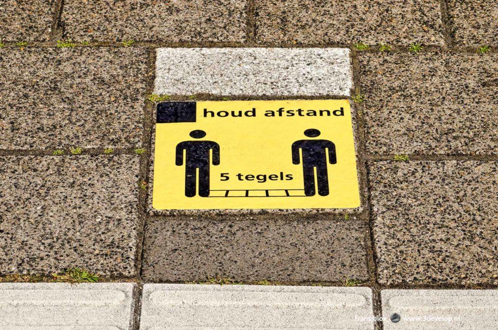 Pavement tile on Dutch railway platform asking to keep 1,5 metre, or vijf tiles, distance, because of covid19