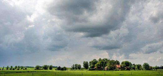 Dreigende lucht boven een dramatisch aangelichte boerderij in de polder langs de IJssel bij Zwolle