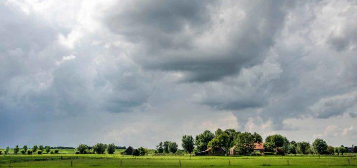 Dramatic sky over a farm under spectacular lighting conditions in the polder along the IJssel river near Zwolle, The Netherlands