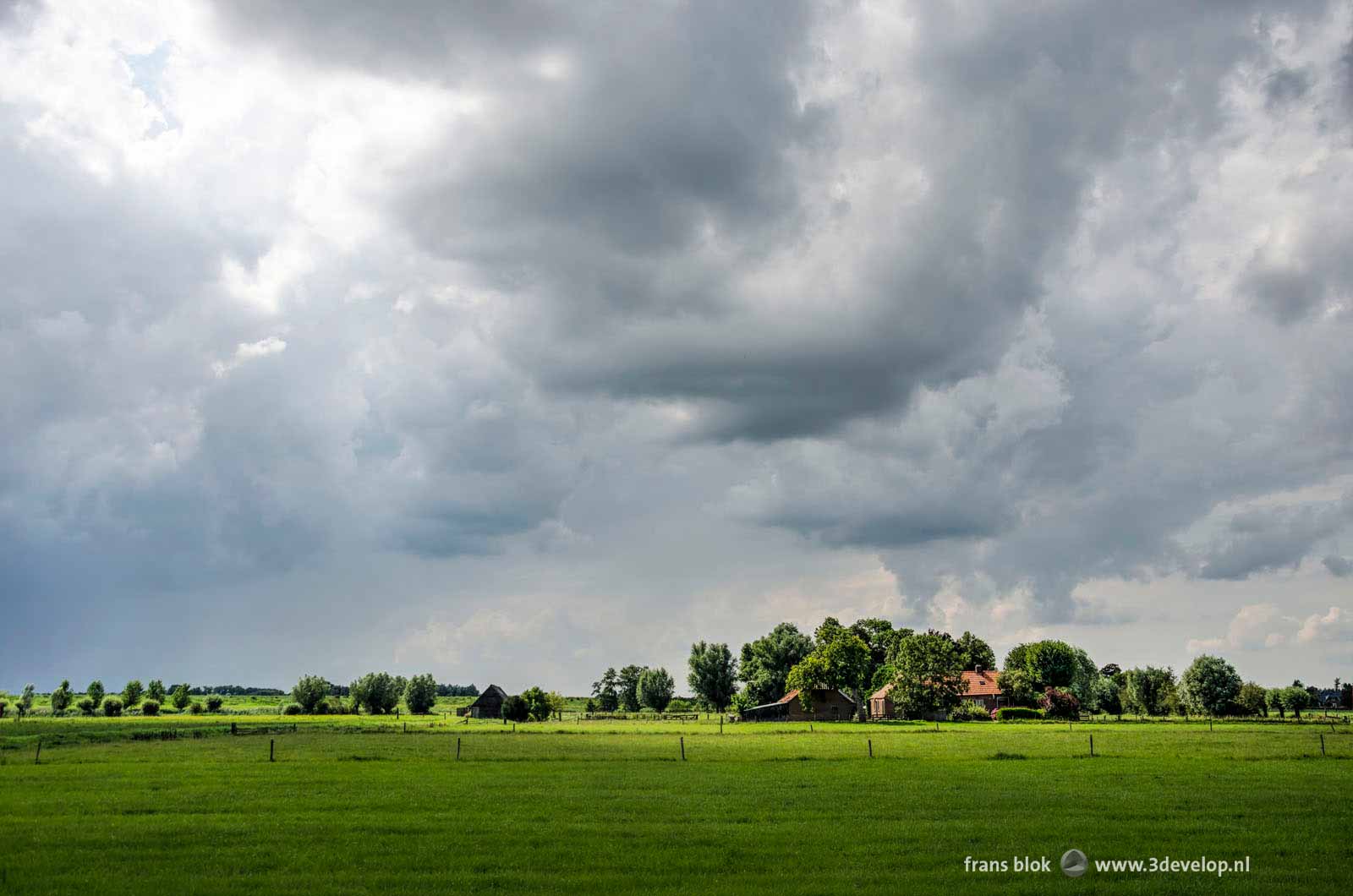 Dramatic sky over a farm under spectacular lighting conditions in the polder along the IJssel river near Zwolle, The Netherlands