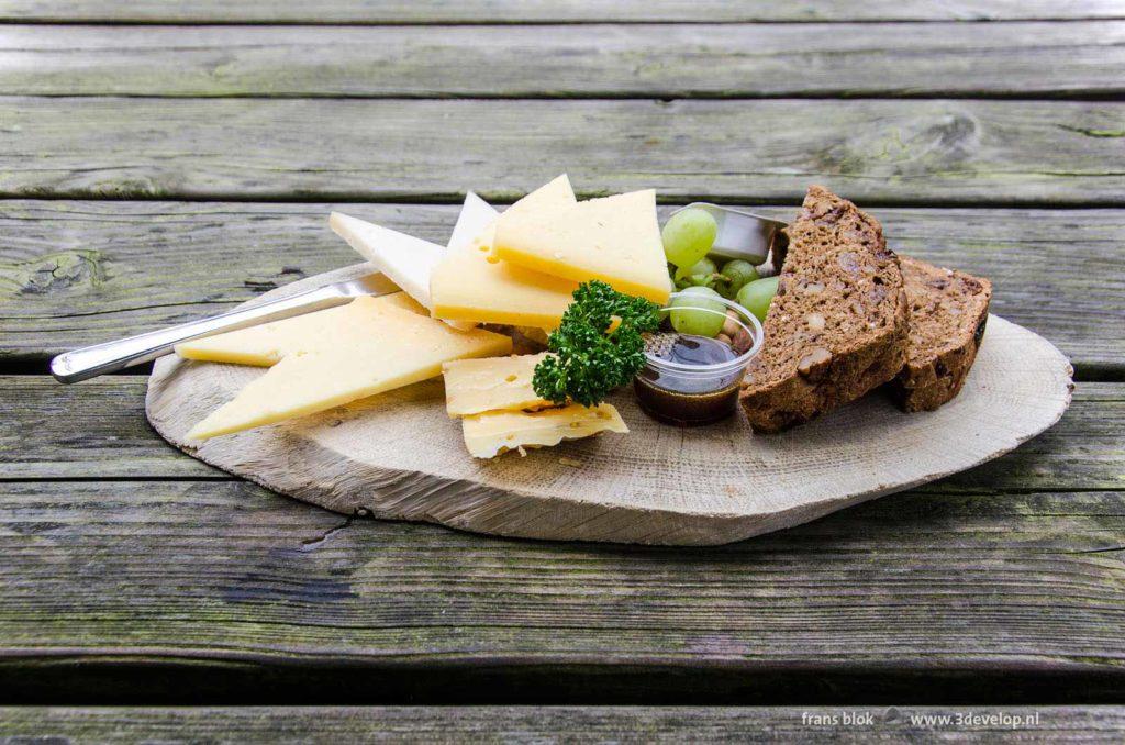 Cheese plate with honey, parsley, grapes and bread on a wooden table