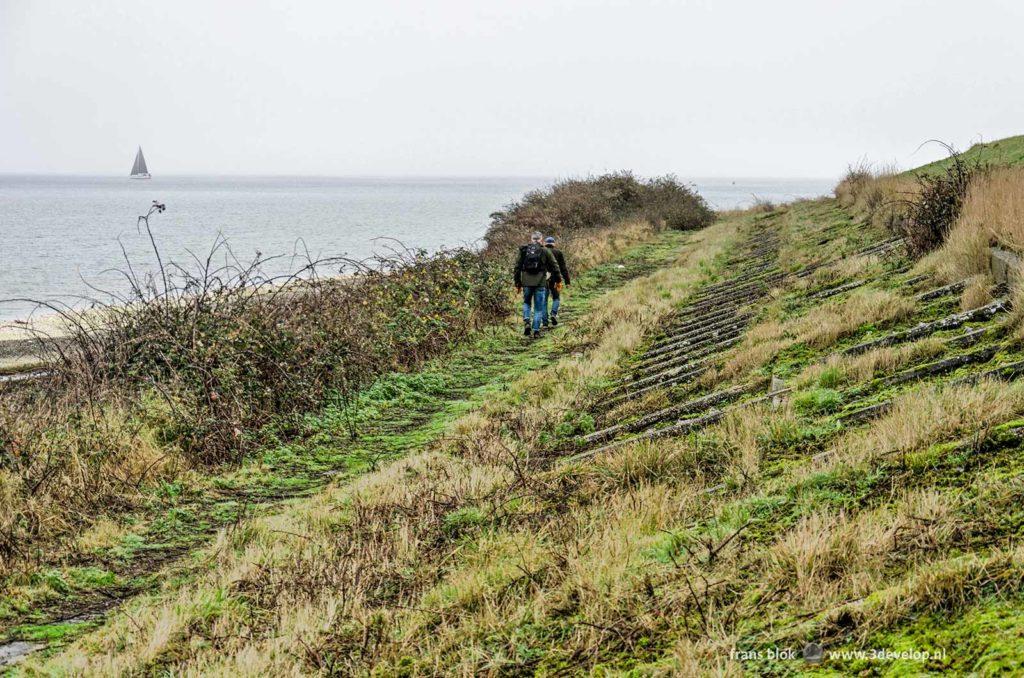 Hikers passing the former sea defense constructions on the north bank of the island of Schouwen-Duiveland, the Netherlands on a misty day