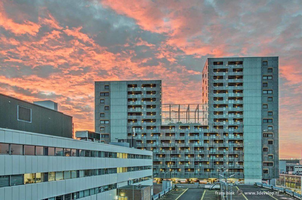 Spectacular sky at sunrise over an office building, a residential complex and a parking lot in downtown Rotterdam, The Netherlands