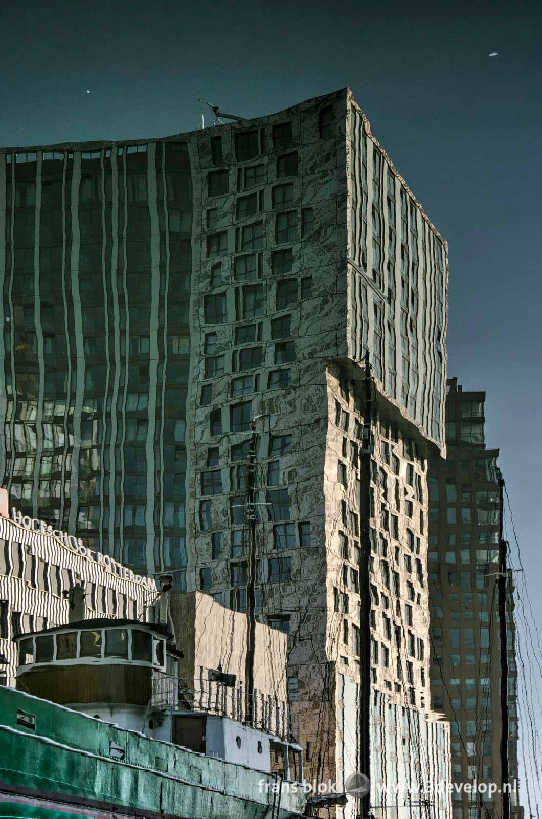 Reflection of a historic vessel and the recently completed residential tower Our Domain in the water of Wijnhaven harbour in Rotterdam, The Netherlands