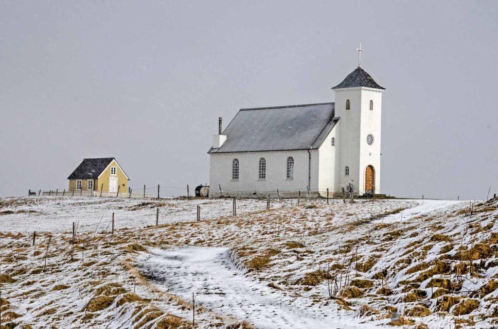 De bibliotheek en de kerk op een besneeuwde heuvel op het IJslandse eiland Flatey