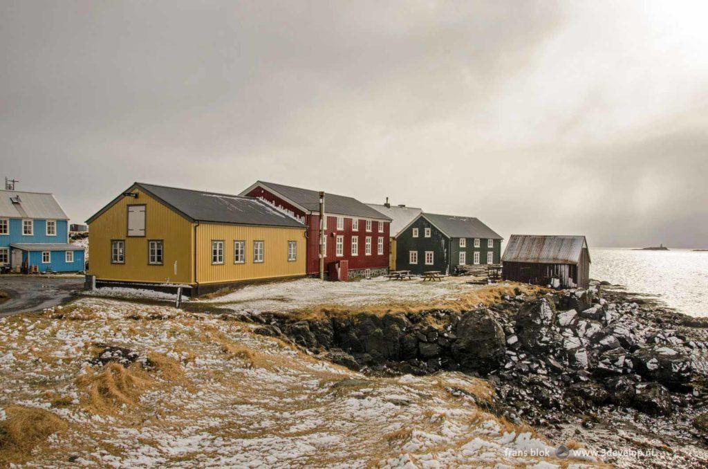 Huizen in primaire kleuren onder een fraaie lucht in de winter op het IJslandse eiland Flatey