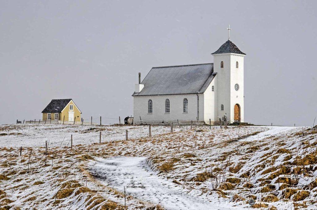 The church and library on the island of Flatey in Iceland surrounded by fields with fresh snow in May