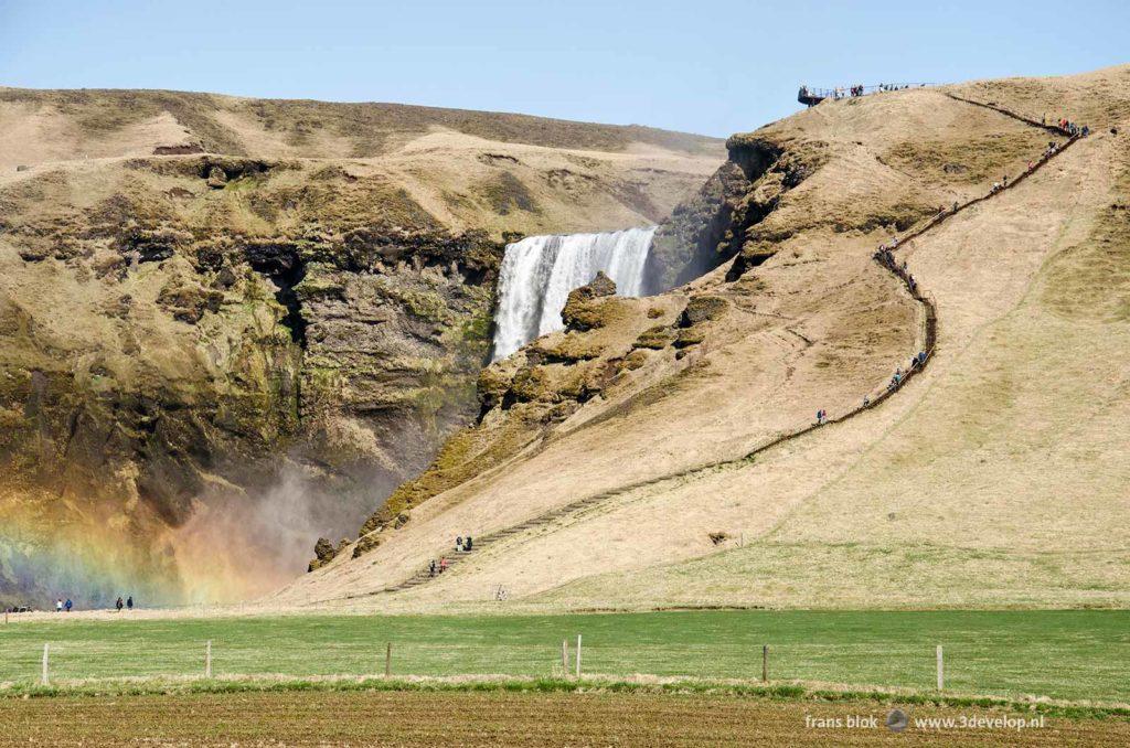 Skogafoss waterfall in Iceland with a rainbow and a very tall staircase