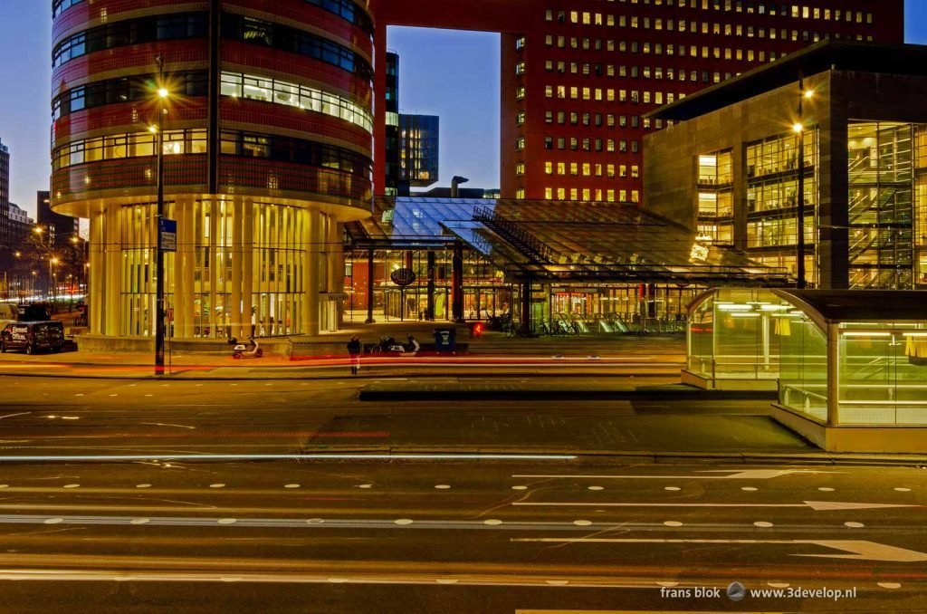 Wilhelminaplein in Rotterdam during the blue hour, with lighttrails from the morning rush hour, the metro entrance and some buildings including the court and the tax office