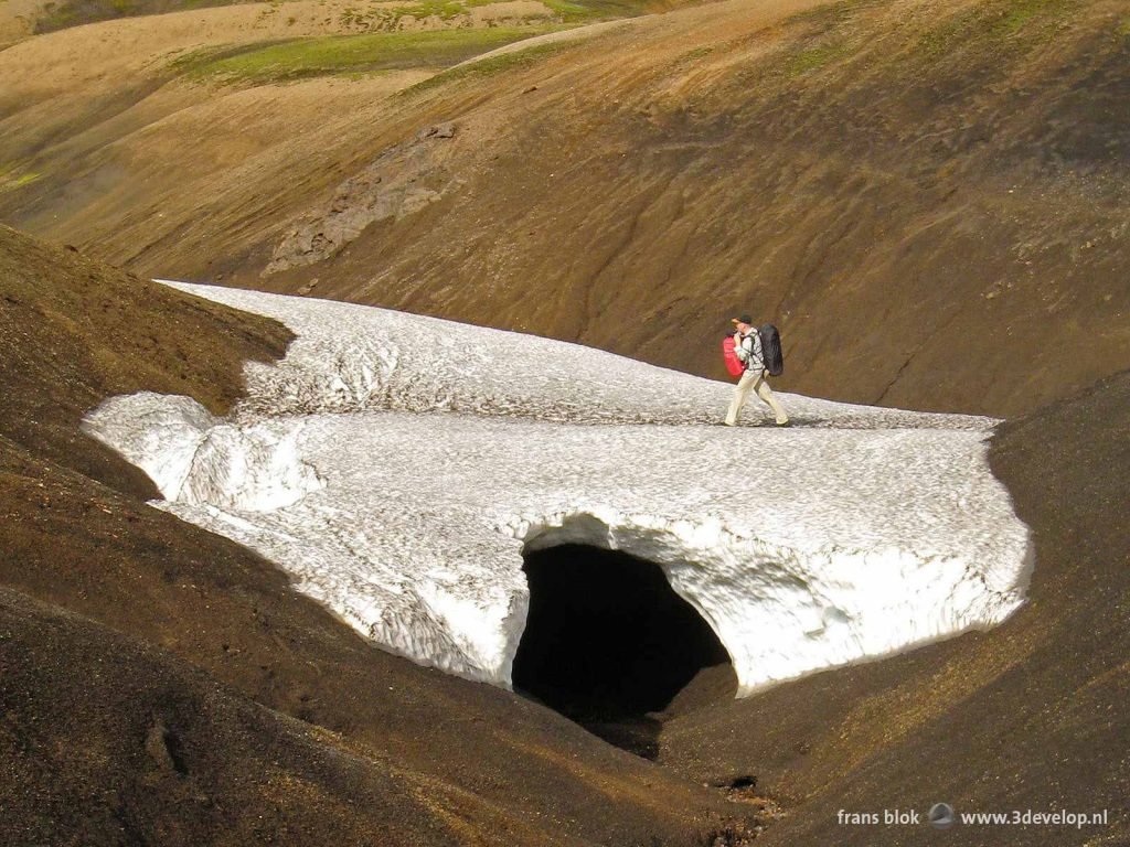 Hiker with backpack walks across a snow field at the Laugavegur in Iceland