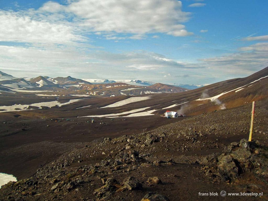 Reddish brown highlands with patches of snow and a hut for hikers near Hraftinusker in Iceland