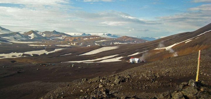 Reddish brown highlands with patches of snow and a hut for hikers near Hraftinusker in Iceland