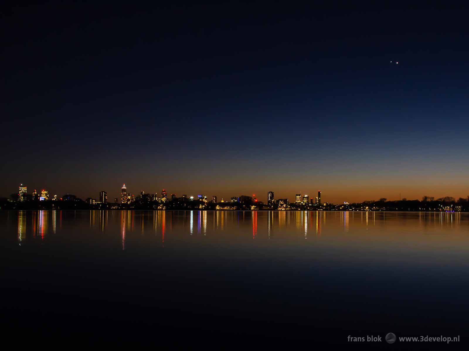 Conjunction of the planets Venus and Jupiter above lake Kralingse Plas in Rotterdam with the city's skyline in the background