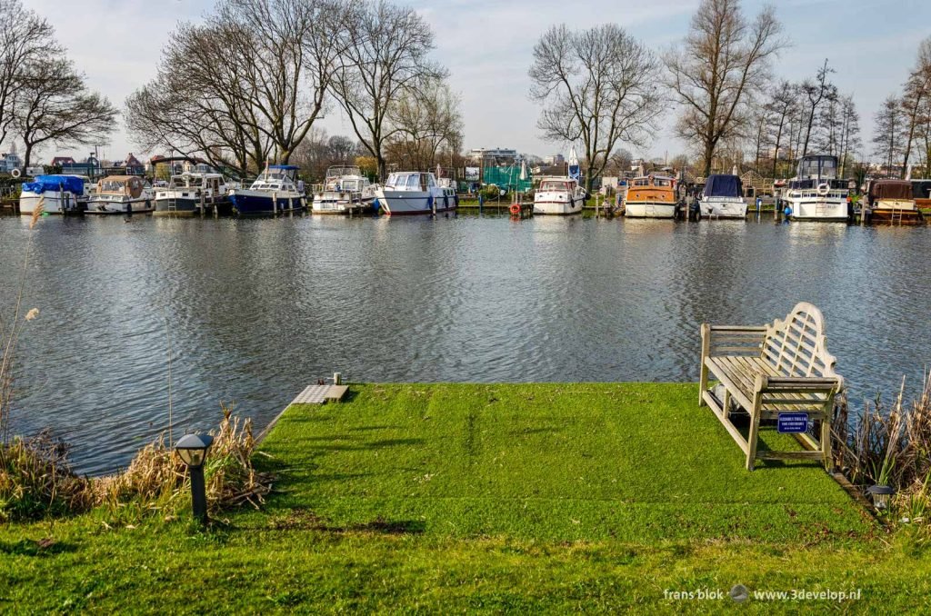 Little platform with artificial grass and a bench on the bank of the river Rotte in Rotterdam