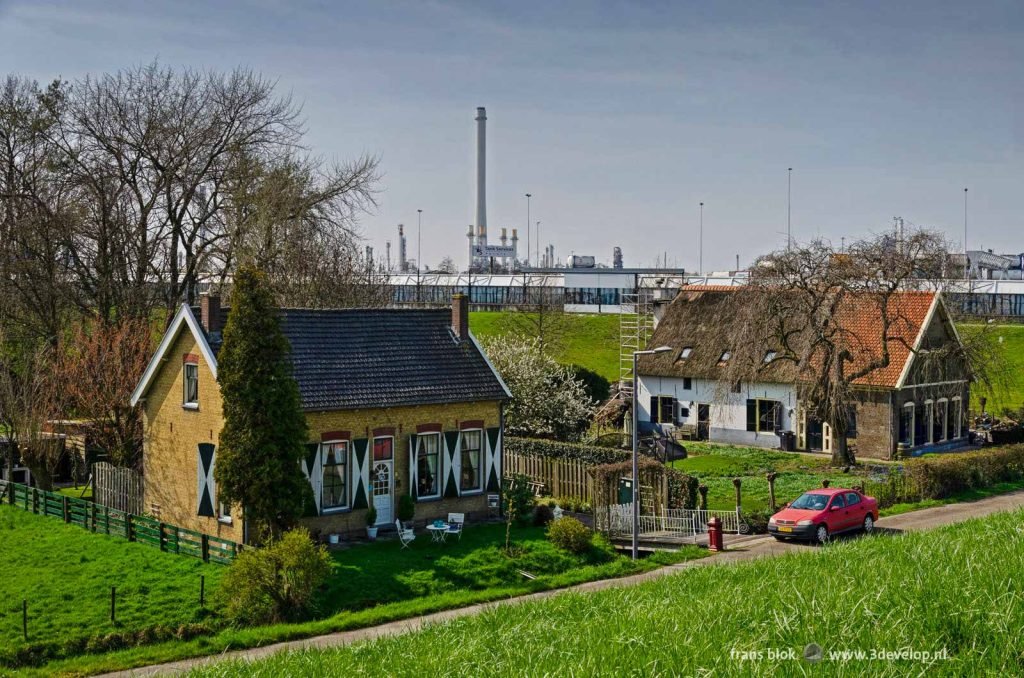 Two farmhouses in Pernis with in the background the Rotterdam ringroad and the Shell refinery