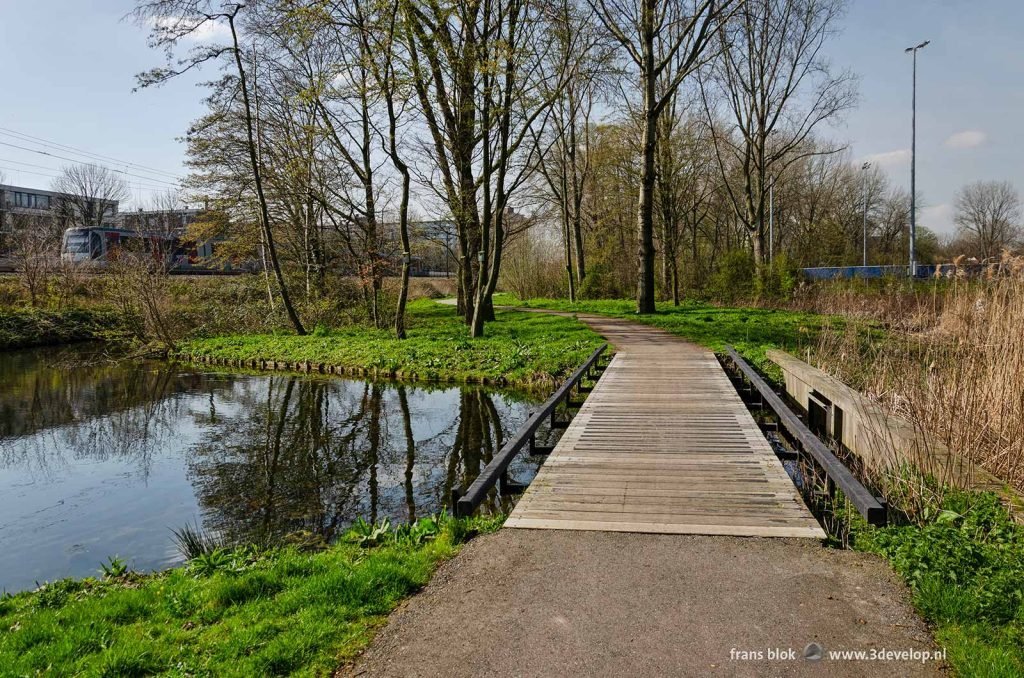 Footpath with bridge in a green zone along the metro tracks in the neighbourhood of Nieuwland, Schiedam, The Netherlands