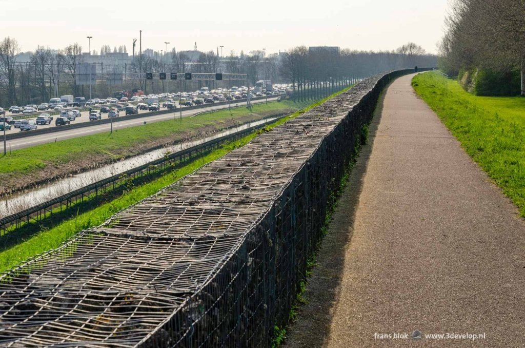 Walking path on the noise barrier at Nieuw Terbregge in Rotterdam with traffic jams on the highway in both directions