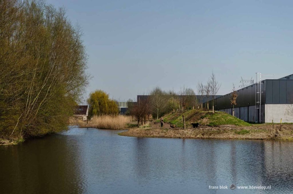 Walking path between industrial halls and a green strip in the Rotterdam district of IJsselmonde