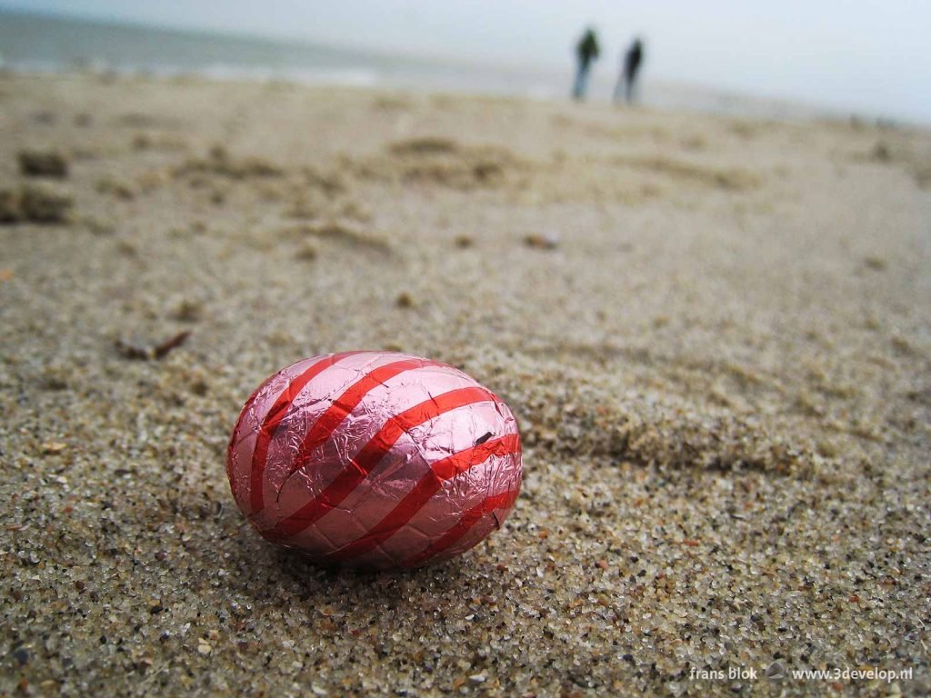 Close up of a red Easter egg on a sandy beach