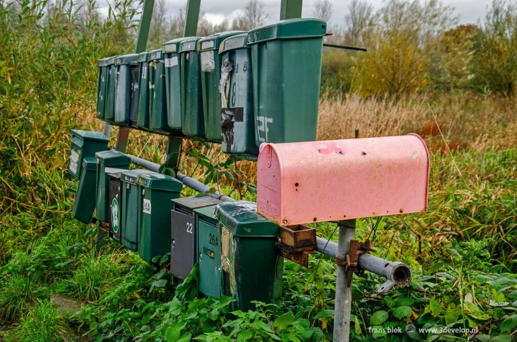 Quirky pink mailbox next to twenty average ones