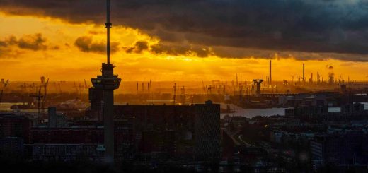 De zon gaat vlammend onder in de Rotterdamse haven achter de Euromast