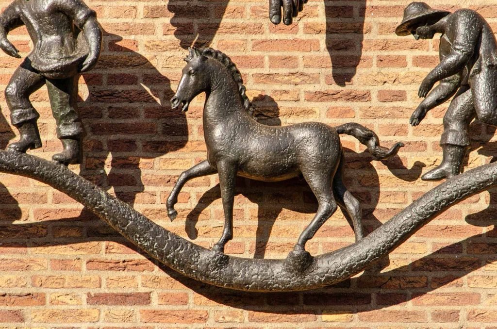 Bronze horse against a brick facade, part of a sculpture named Prosperity on a bank building in Rotterdam