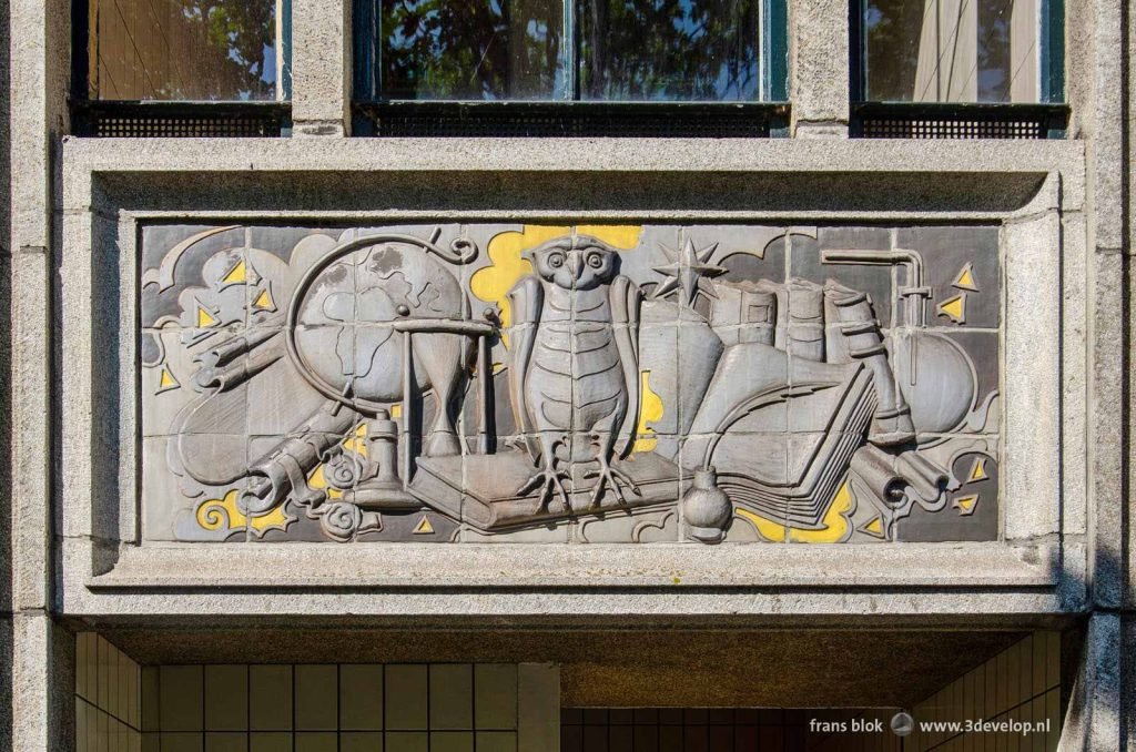 Facade stone with an owl surrounded by scientific instruments on a residential building in Rotterdam