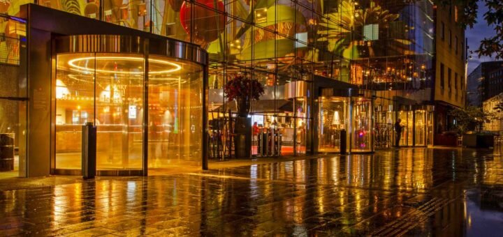 Het interieur en kunstwerk van de Markthal in Rotterdam weerspiegelt in de natte bestrating tijdens de avondschemering